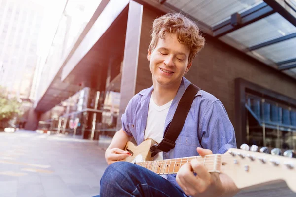 Jovem músico com guitarra na cidade — Fotografia de Stock