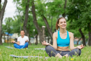 Genç çift yeşil çimenlerin üzerinde meditasyon
