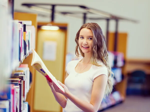 Glückliche Studentin, die in der Bibliothek Bücher abholt — Stockfoto