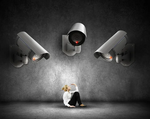 Junge verängstigte Frau im Zimmer unter Kontrolle der Videokamera — Stockbild Kamera behält Frau im Auge — Stockfoto