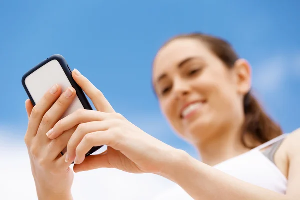 Female runner with her mobile smart phone standing outdoors — Stock Photo, Image