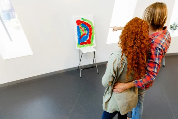 Jeune couple caucasien debout dans une galerie et contemplant des œuvres d'art — Photo