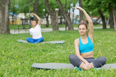 Genç çift yeşil çimenlerin üzerinde meditasyon