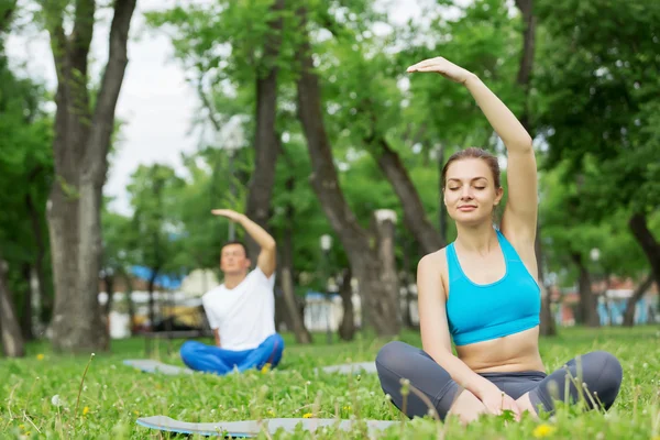 Jovem casal meditando na grama verde — Fotografia de Stock