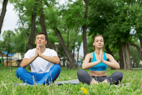 Genç çift yeşil çimenlerin üzerinde meditasyon — Stok fotoğraf