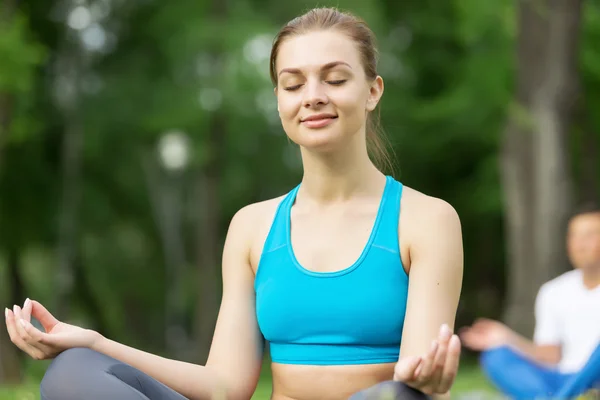 Mladý pár, meditovat na zelené trávě — Stock fotografie