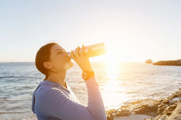 ビーチで水を飲む女性 — ストック写真