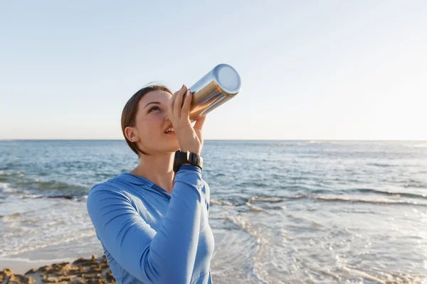 Γυναίκα πόσιμο νερό στην παραλία — Φωτογραφία Αρχείου