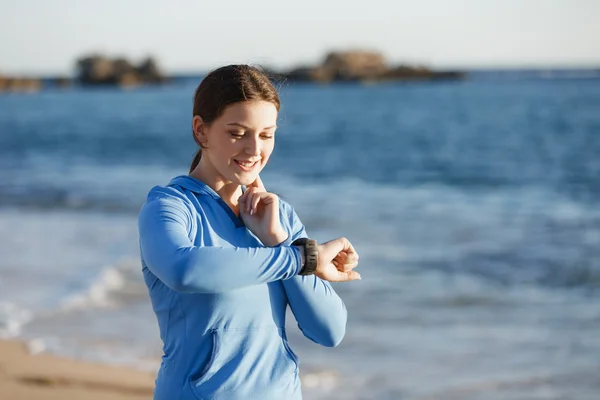 Mujer corredora con monitor de frecuencia cardíaca corriendo en la playa —  Fotos de Stock