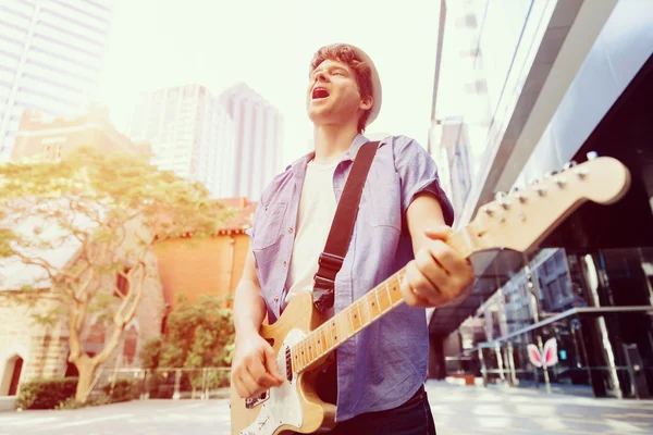 Joven músico con guitarra en la ciudad — Foto de Stock