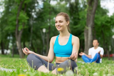 Genç çift yeşil çimenlerin üzerinde meditasyon