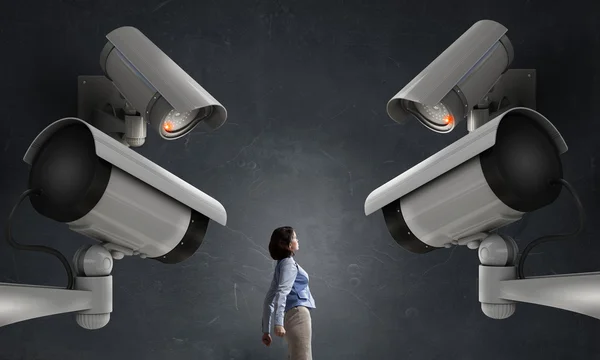 Junge Frau im Zimmer unter Kontrolle der Videokamera — Stockbild Kamera behält Frau im Auge — Stockfoto