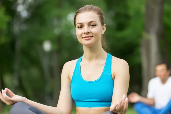 Genç çift yeşil çimenlerin üzerinde meditasyon — Stok fotoğraf