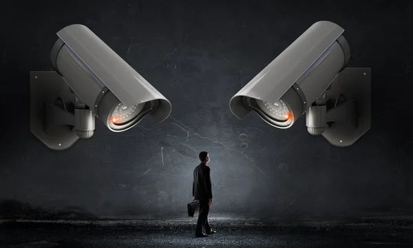 Junger verängstigter Mann im Zimmer unter Kontrolle der Videokamera — Stockbild Kamera hat Mann im Auge — Stockfoto