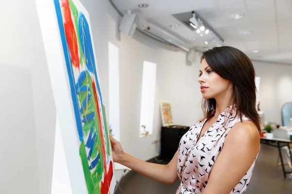 Jeune femme caucasienne debout dans la galerie d'art devant des peintures — Photo