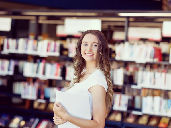 Glückliche Studentin mit Büchern in der Bibliothek — Stockfoto