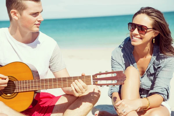 Smukke unge mennesker med guitar på stranden - Stock-foto