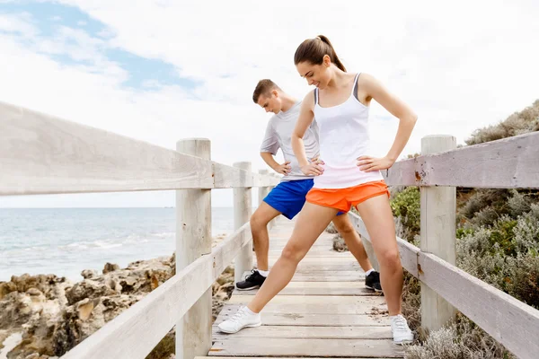 Des coureurs. Jeune couple exerçant et stertching sur la plage — Photo