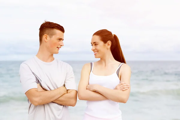 Young couple looking at each other while standing on beach — Stock Photo, Image