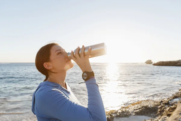 ビーチで水を飲む女性 — ストック写真