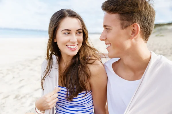 Romántica pareja joven sentada en la playa — Foto de Stock