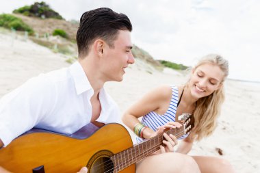 Genç çift aşık sahilde gitar çalmak