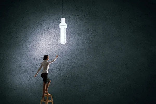 Empresária atingindo lâmpada — Fotografia de Stock