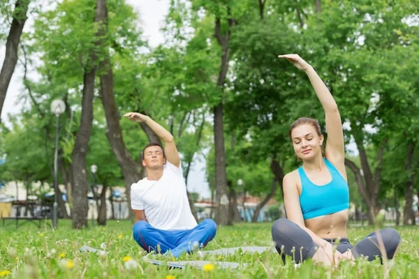 Jeune couple méditant sur l'herbe verte — Photo