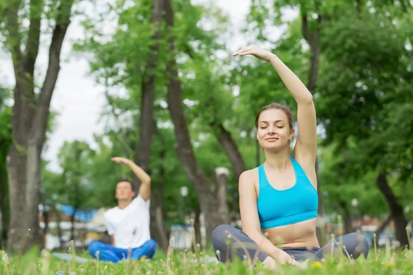 Jovem casal meditando na grama verde — Fotografia de Stock