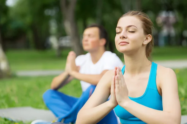 Genç çift yeşil çimenlerin üzerinde meditasyon — Stok fotoğraf