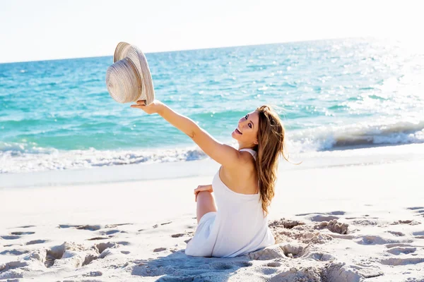 Jonge vrouw zittend op het strand — Stockfoto