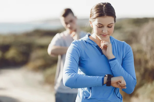 Runner donna con cardiofrequenzimetro in esecuzione sulla spiaggia — Foto Stock