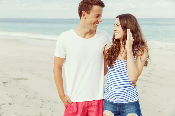 Romántica pareja joven de pie en la playa — Foto de Stock