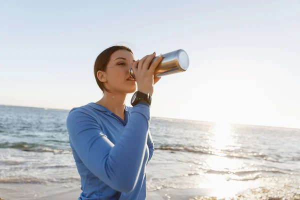 Frau trinkt Wasser am Strand — Stockfoto