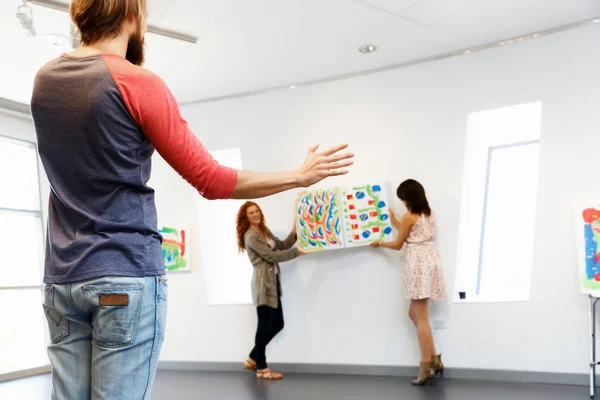 Jóvenes artistas en galería colgando pintura en las paredes —  Fotos de Stock