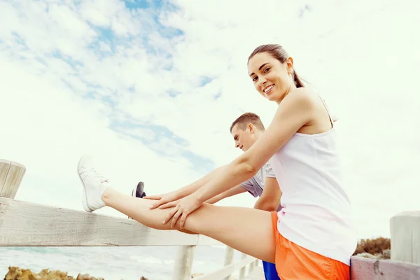 Corredores. Pareja joven haciendo ejercicio y esteretizando en la playa — Foto de Stock