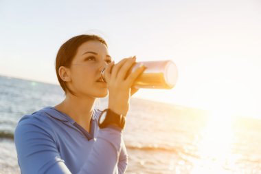 Kumsalda su içen kadın