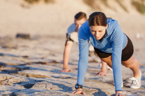 Jong (echt) paar doen push-ups op oceaan strand — Stockfoto