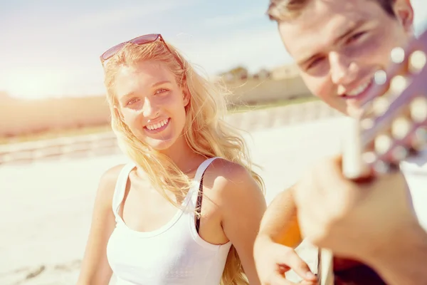 Giovane coppia che suona la chitarra sulla spiaggia in amore — Foto Stock