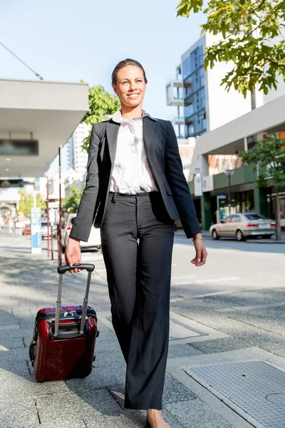 व्यवसायी महिला शहर में चलने वाले सूटकेस बैग खींच रही — स्टॉक फ़ोटो, इमेज
