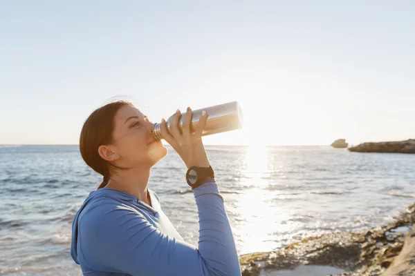 ビーチで水を飲む女性 — ストック写真