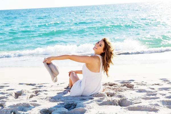 Jonge vrouw zittend op het strand — Stockfoto