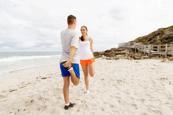 Бігуни. Молода пара вправляється і стерпить на пляжі — стокове фото