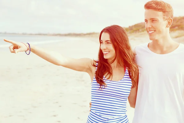 Gelukkige jonge man en vrouw paar samen wandelen op een strand — Stockfoto