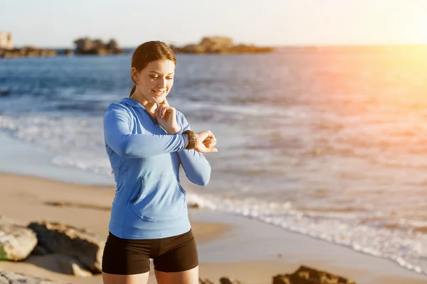 Löpare kvinna med pulsmätare körs på stranden — Stockfoto