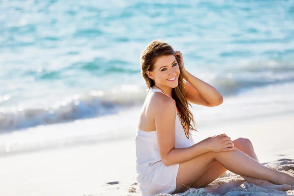 Mujer joven sentada en la playa — Foto de Stock