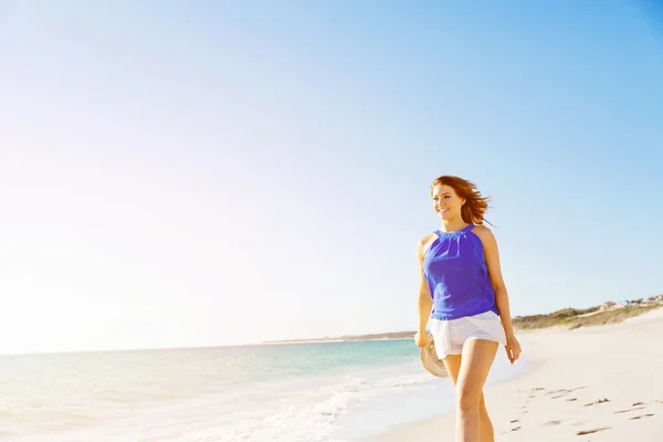 Jeune femme marchant le long de la plage — Photo