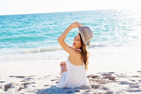 Ung kvinna sitter på stranden — Stockfoto