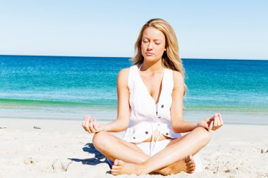 Genç bir kadın sahilde dinleniyor.