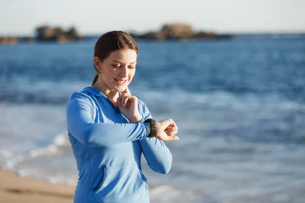 Loper vrouw met hartslagmeter uitgevoerd op strand — Stockfoto